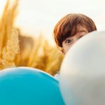 enfant caché derrière un ballon