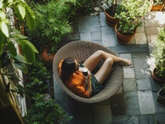 Vue aérienne d'une femme se relaxant avec un café dans un fauteuil en rotin, au cœur d'un aménagement d'un jardin bien-être verdoyant