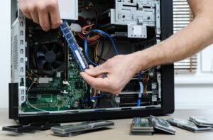 Technicien installant une barrette de mémoire vive RAM dans une tour de PC durant un dépannage informatique