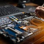 Technicien réparant les composants internes d'un ordinateur portable ouvert lors d'un dépannage informatique à domicile