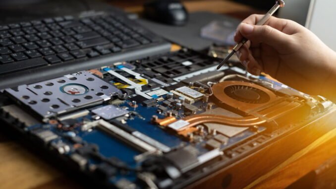 Technicien réparant les composants internes d'un ordinateur portable ouvert lors d'un dépannage informatique à domicile