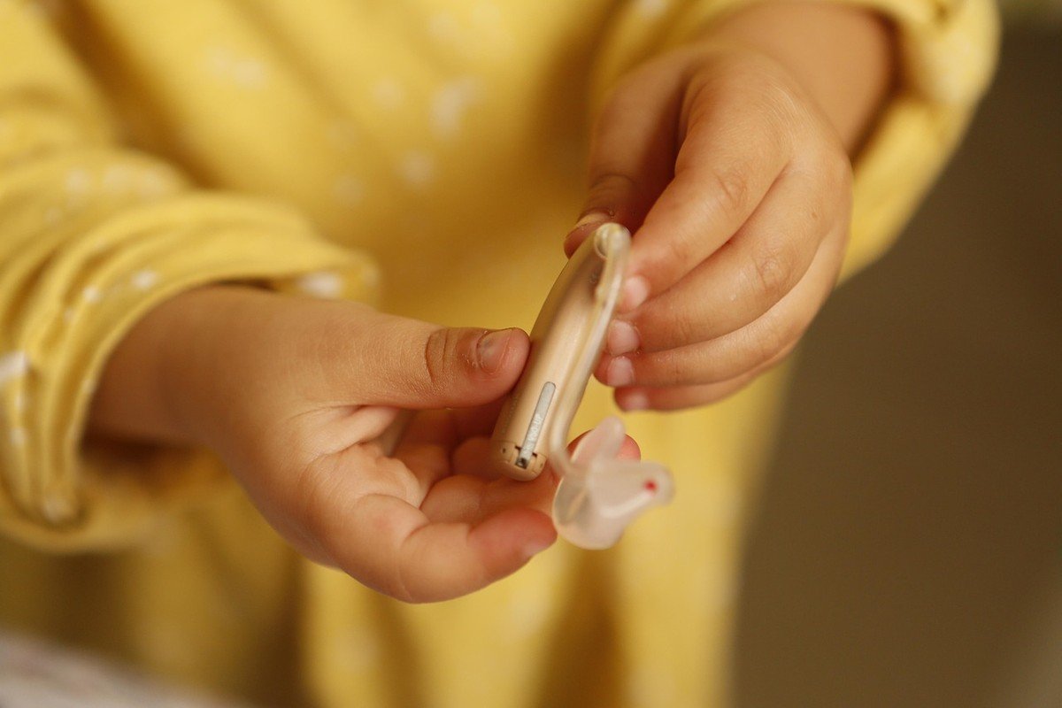 Un enfant en vêtement jaune manipule doucement un petit appareil blanc Un enfant en vêtement jaune manipule doucement un petit appareil blanc