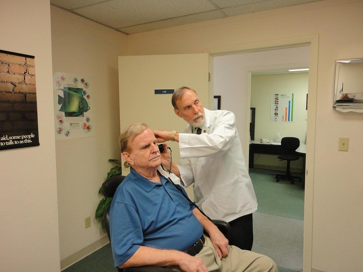 Un professionnel de santé utilise un appareil pour examiner l'oreille d'un homme Un professionnel de santé utilise un appareil pour examiner l'oreille d'un homme
