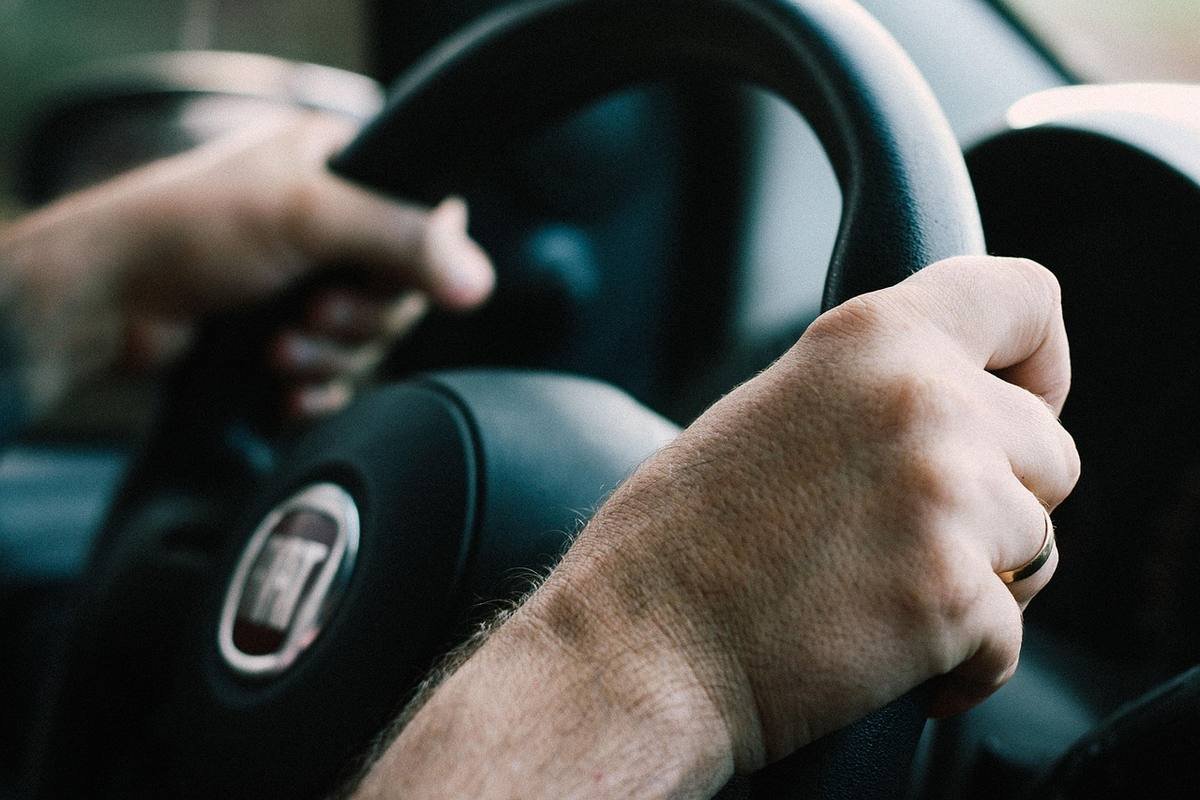 Mains tenant le volant d'une voiture en conduite