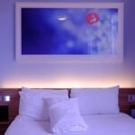 Un lit avec oreillers, tableau mural et éclairage d'ambiance