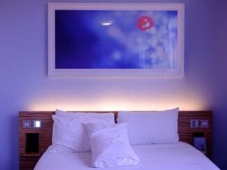 Un lit avec oreillers, tableau mural et éclairage d'ambiance