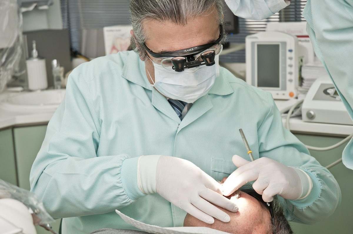 Dentiste en blouse verte opérant sur un patient Dentiste en blouse verte opérant sur un patient