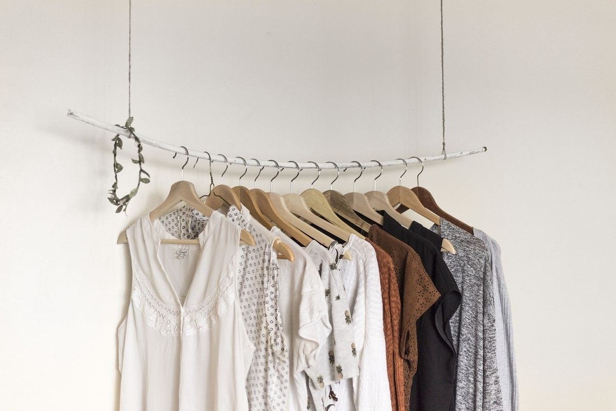 Hangers with clothes on a metal rod against a white wall Hangers with clothes on a metal rod against a white wall