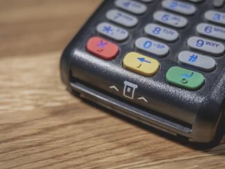 Un terminal de paiement noir avec clavier coloré sur bois