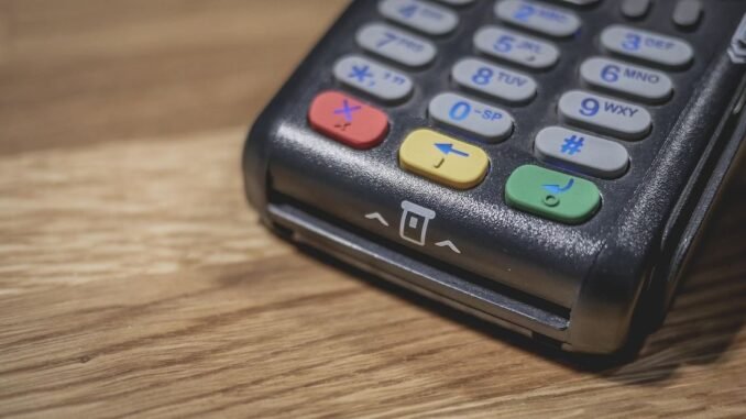Un terminal de paiement noir avec clavier coloré sur bois