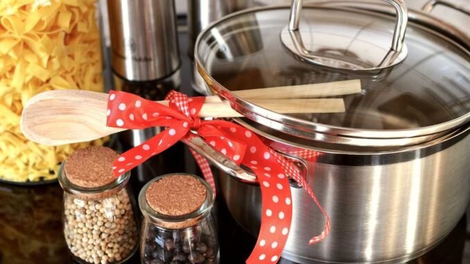 Casserole en acier inoxydable avec couvercle, cuillère en bois et bocaux de légumes